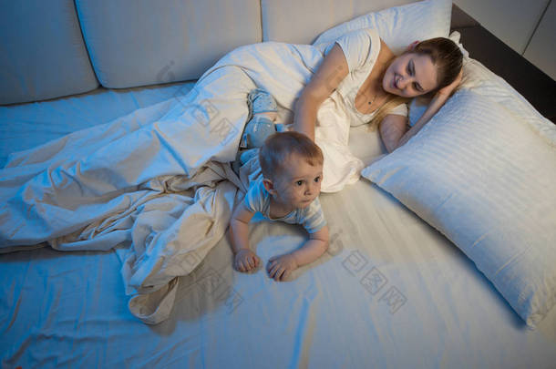 年轻的母亲和她的宝贝儿子在床上<strong>睡</strong>觉