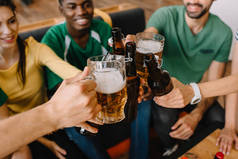 多文化足球爱好者的特写观看庆祝和无比啤酒瓶和杯子