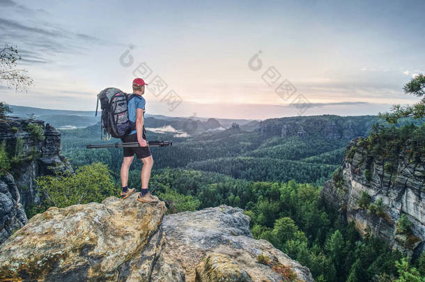 沉重的背包和三脚架在手中的<strong>高大</strong>摄影师站在岩石角度和观看到深雾谷波纹管