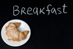 在黑板上的字早餐盘子上牛角面包