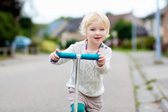 骑上推滑板车在街道上的小女孩