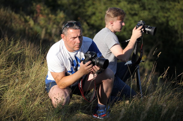 摄影师父亲和儿子在大自然中起飞。父亲教儿子使用照相机的权利。两个朋友的会面