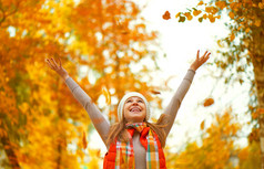 快乐的女孩抛出了秋天的落叶，在园内为户外行走