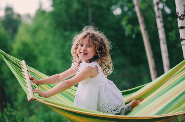 <strong>happy</strong> child girl relaxing in hammock on summer camp in forest. Outdoor seasonal activities for kids.