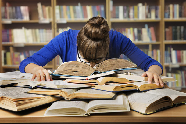 学生在学习上的书，睡觉累女孩读图书馆的书