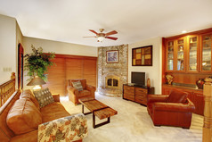 舒适楼上的客厅在棕色的色调与石壁炉在角落里.