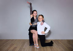 年轻的男孩和女孩摆在灰色的舞蹈工作室。舞厅跳舞概念