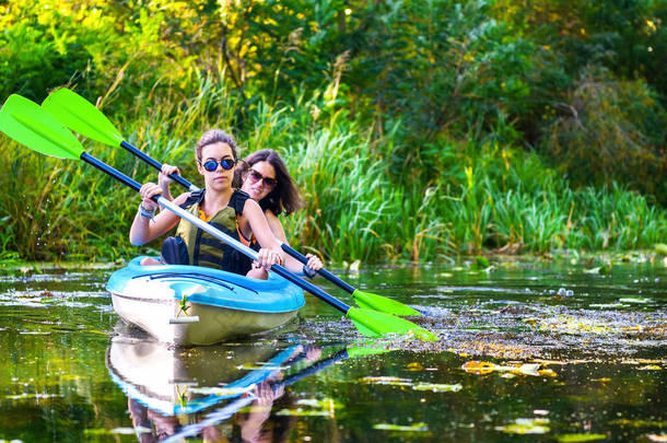 家庭皮划艇、在独木舟上划艇的母亲和孩子、积极的夏季周末和假期、体育和健身概念