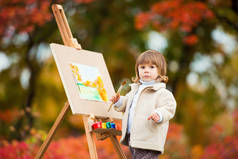 秋天的女婴画在秋叶公园, 小孩画画, 孩子们的创造力.