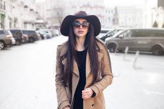 户外肖像年轻漂亮时髦的女人与长发漫步在街上。模型看一边, 身穿时尚经典米色大衣, 帽子, 配件。女性时尚, 美容理念