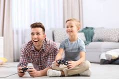 可爱的小男孩与父亲在家里玩电子游戏