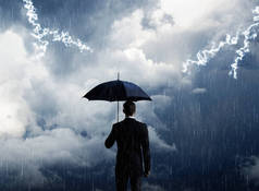 有雨伞的商人站在暴风雨背景下.