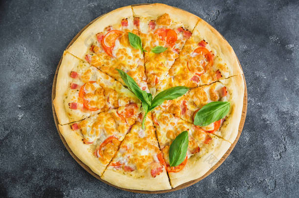 美味的比萨饼配培根, 奶酪, 西红柿在黑暗的背景。平躺, 顶部视图。食品背景