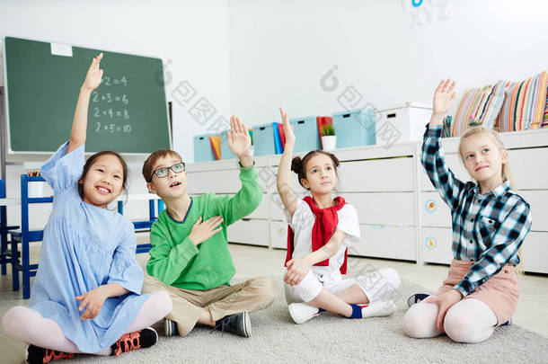 小学学童小组在课上举手回答老师的问题
