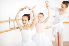 小芭蕾舞演员与她的手臂头跳舞, 而老师帮助她的朋友附近