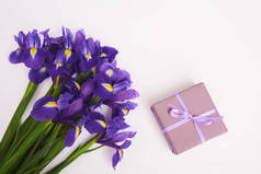 贺卡与春天紫色的虹膜花和礼品盒在白色的背景。顶部视图