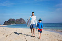 幸福的两个家庭, 父子, 漫步在沙滩上捧冲浪板, 冒险度假的概念