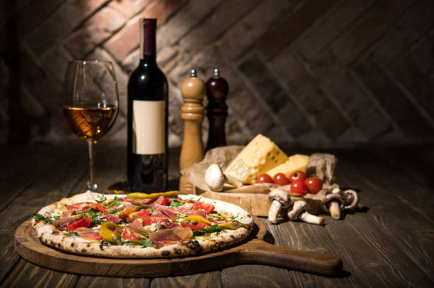 意大利比萨, 香料, 奶酪, 樱桃西红柿和葡萄酒瓶在木质表面的<strong>选择性</strong>聚焦