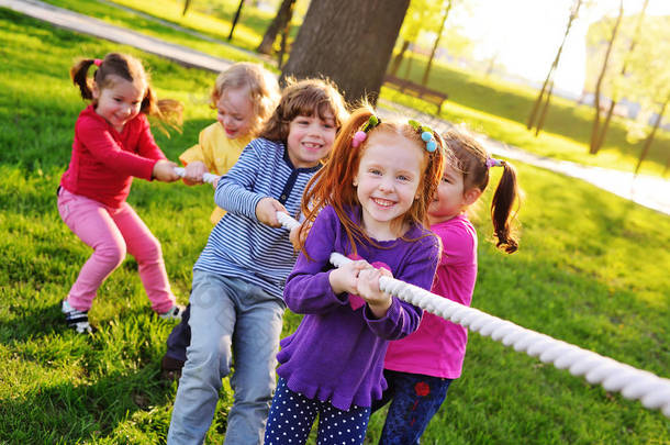 一群小学龄前儿童在公园里玩<strong>拔河比赛</strong>。.
