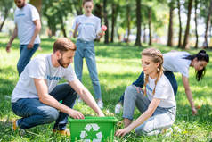 青年志愿者用绿色回收箱清洁草坪