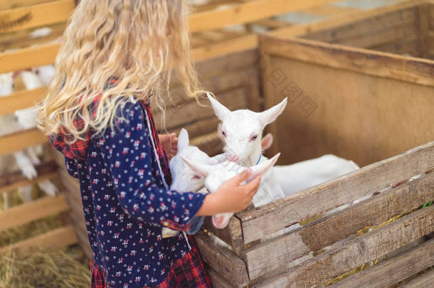 儿童抱山羊在农场的侧面视图