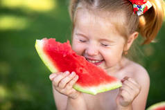 孩子在花园里吃西瓜。孩子们在户外吃水果。儿童健康小吃。小女孩在花园里拿着一片西瓜。儿童园艺