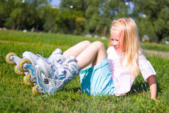 休闲, 童年, 户外运动和运动概念-可爱的金发小女孩坐在绿草溜冰鞋