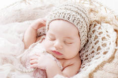 甜美的新生婴儿睡觉。3周大的新生男孩躺在篮子里用针织格子。漂亮的新生男孩的肖像。特写图像