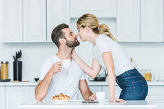 美丽的年轻夫妇在爱能亲吻, 而在一起吃早餐