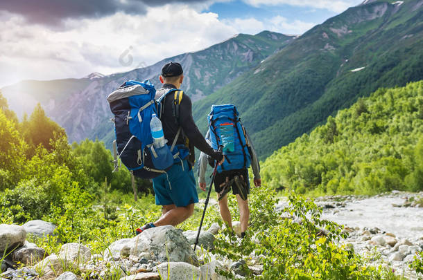 徒步旅行在山上。爬山。游客们带着背包徒步走近河边的洛基路。野生自然与美丽的看法。上斯瓦涅季亚, 乔治亚州的体育旅游。徒步旅行者和登山者在坐骑.