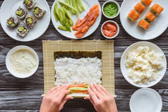 用大米、紫菜、鲑鱼和鳄梨制作寿司的人被裁剪的照片