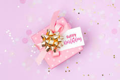 粉红色礼品盒与生日快乐标签在紫色装饰背景