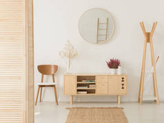 木制柜子与花和石南之间时尚的棕色椅子和木制衣架, 真正的照片