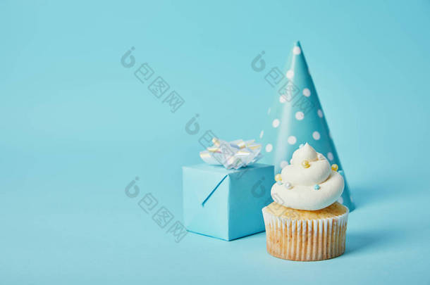 党帽子, 礼品盒和美味的纸杯蛋糕在蓝色背景