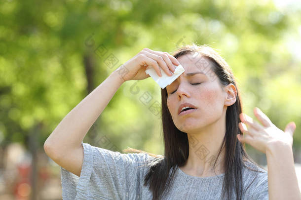 在温暖的夏日用擦拭擦干汗水的女人