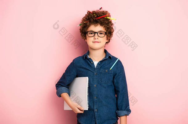 戴<strong>眼镜</strong>高兴的孩子，带着<strong>彩色</strong>铅笔，卷发，手持粉红记事本