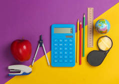 回学校去紫色黄色背景的学校和办公用品。教育，学习概念。顶部视图.