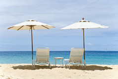 两个白色的沙滩椅和遮阳伞