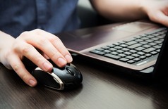 计算机鼠标上人的手。桌上的笔记本电脑.