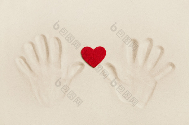两只手打印在沙滩上用一颗红色的心。符号的概念
