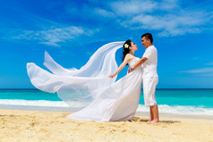 亚洲新娘和新郎在热带的海滩上。婚礼和蜜月