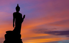 走在黄昏剪影的佛教雕像的姿势