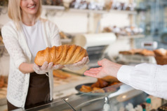 Skillful female baker is serving her customer