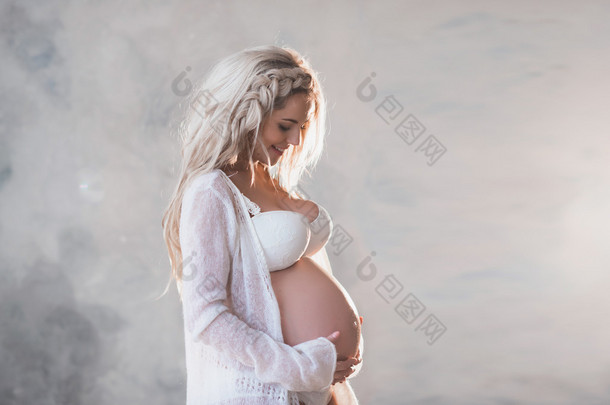 白色内衣和长长的头发美丽的怀孕女人的画像