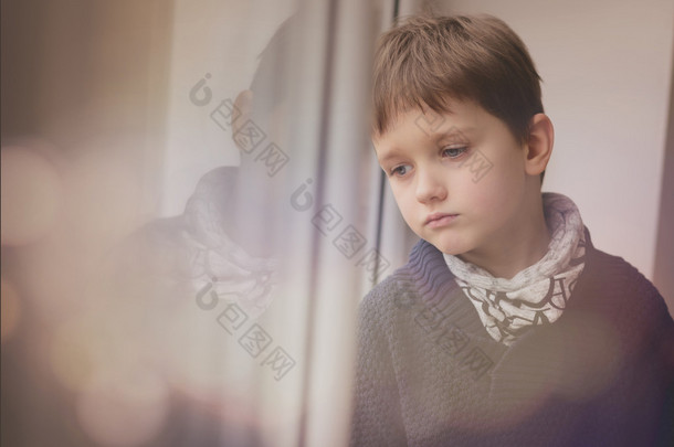 望着窗外的悲哀周到的小男孩.