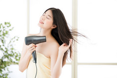 亚洲美容女人吹风机洗完澡后干燥的头发