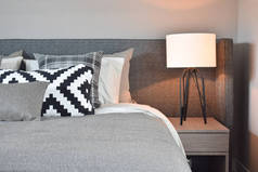 黑与白纹枕头灰色毯子和白色灯罩床头桌灯