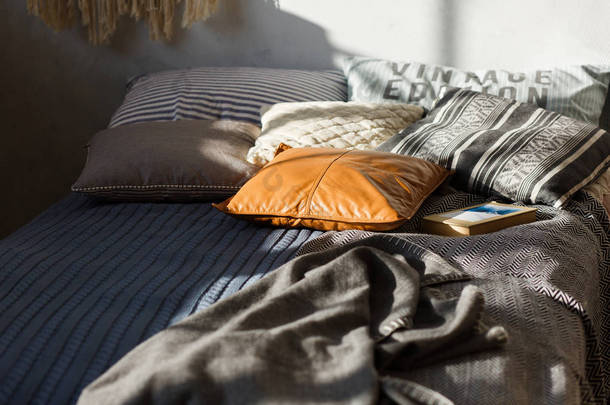 灰色的床, 彩色的枕头和质感的墙壁在背景。特写镜头, 专注于真皮枕头