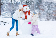 快乐的母女一起在冬天的森林里堆雪人