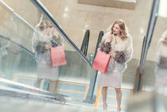 购物中心自动扶梯上购物袋时尚女性的高角度视角